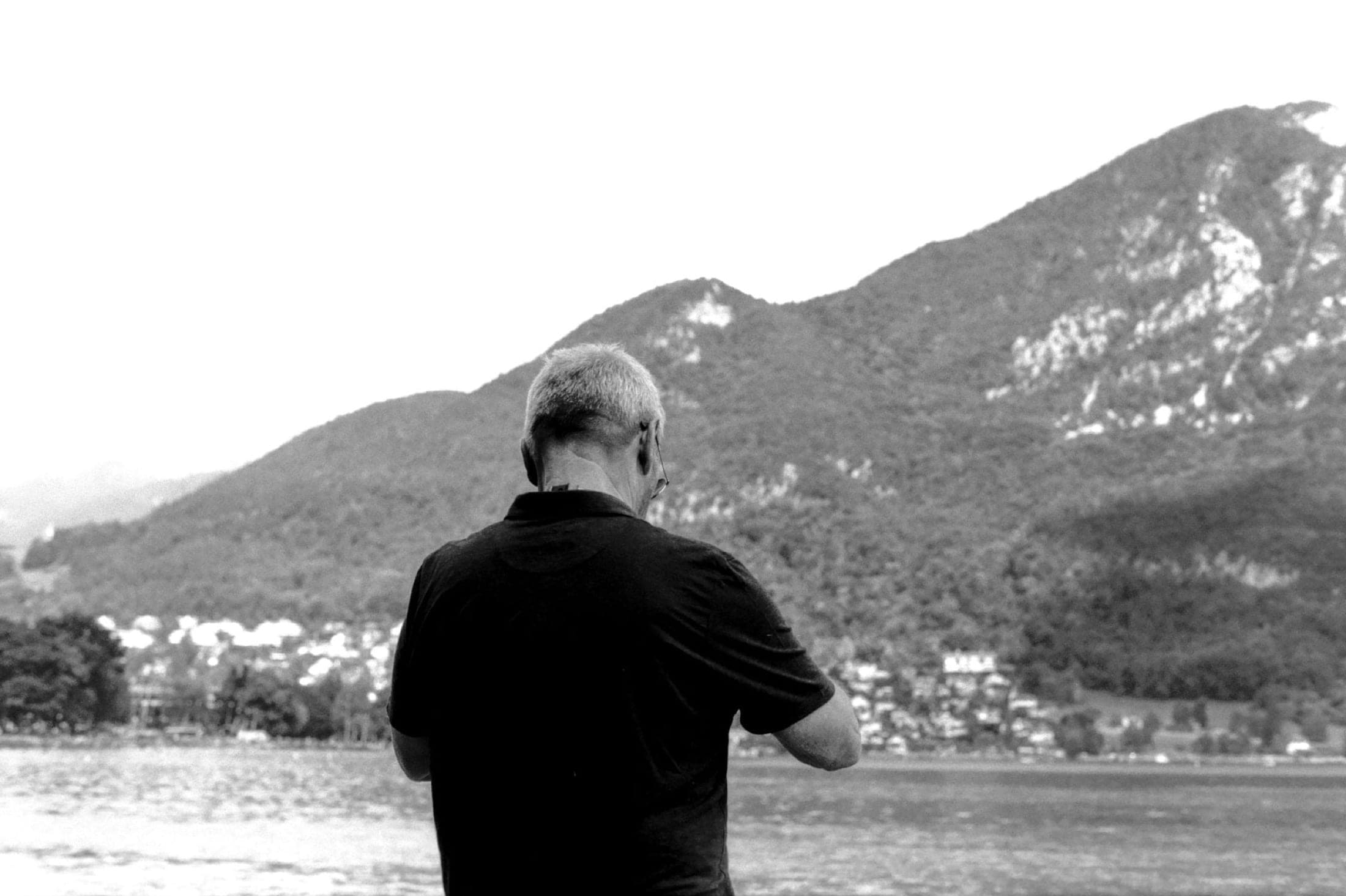 De dos face au lac et à la montagne, le photographe vérifie son boîtier entre deux prises.