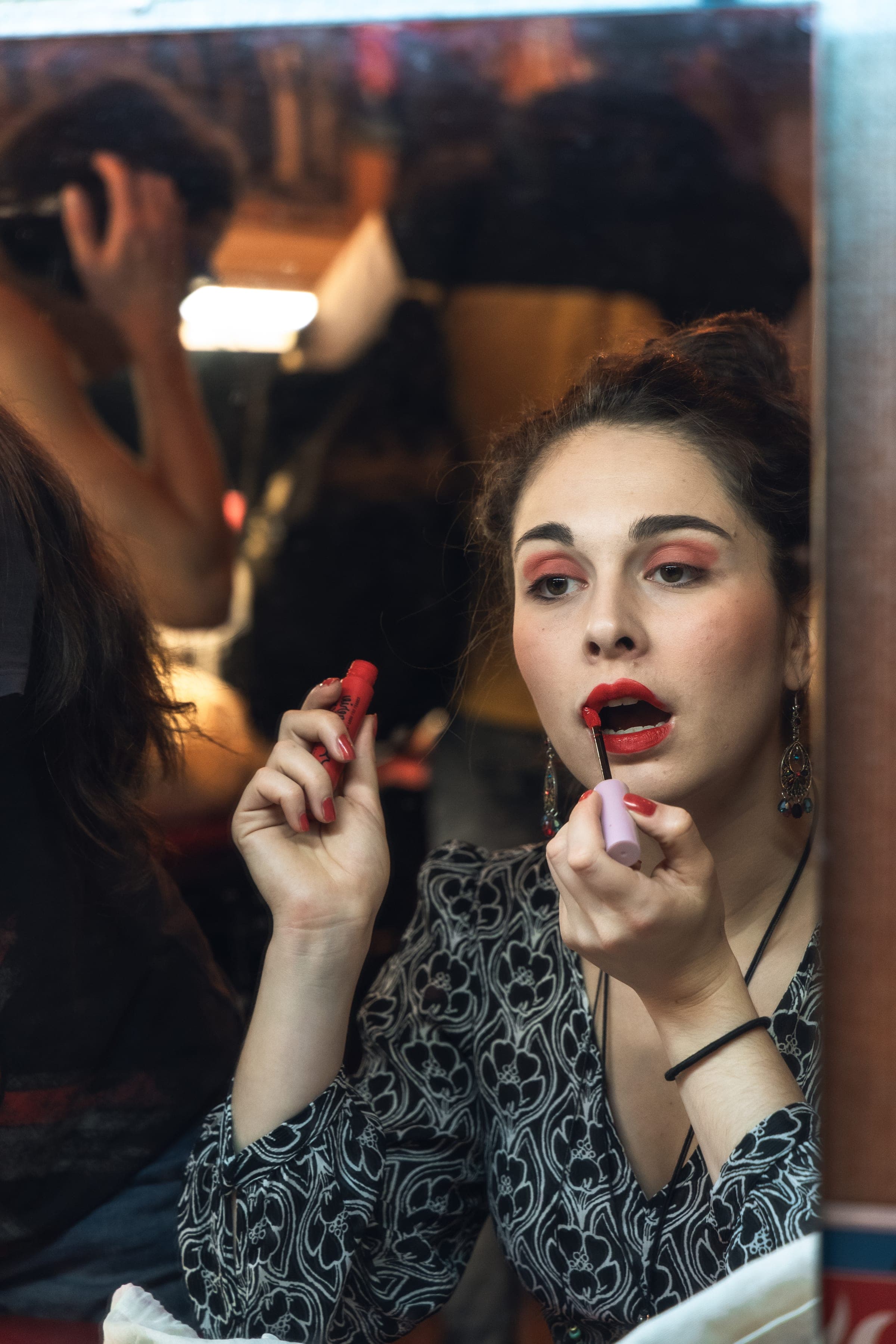 Une comédienne se maquille devant le miroir de sa loge, rouge à lèvres à la main