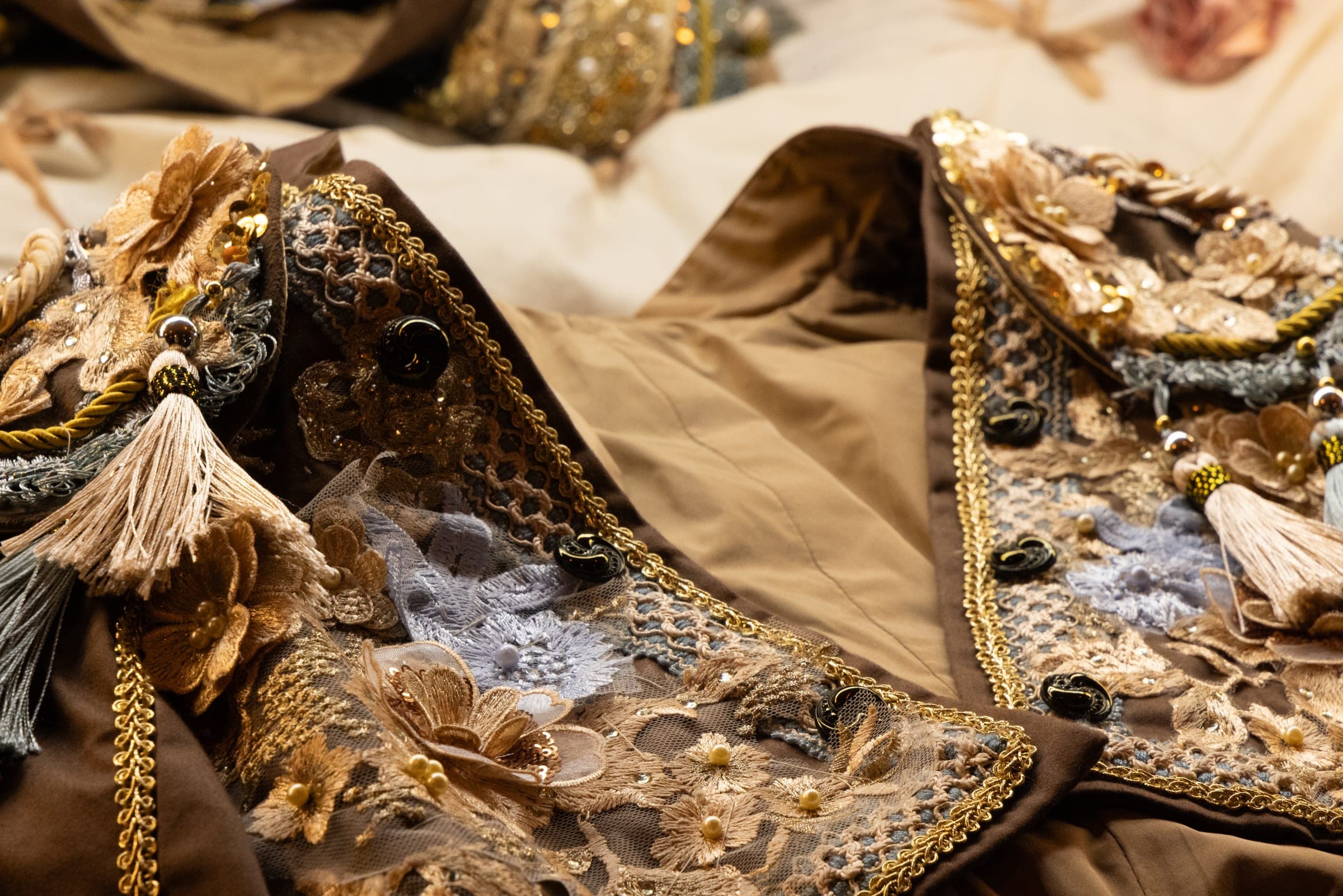 Costumes de scène brodés d'or et de perles, posés à plat avant l'habillage