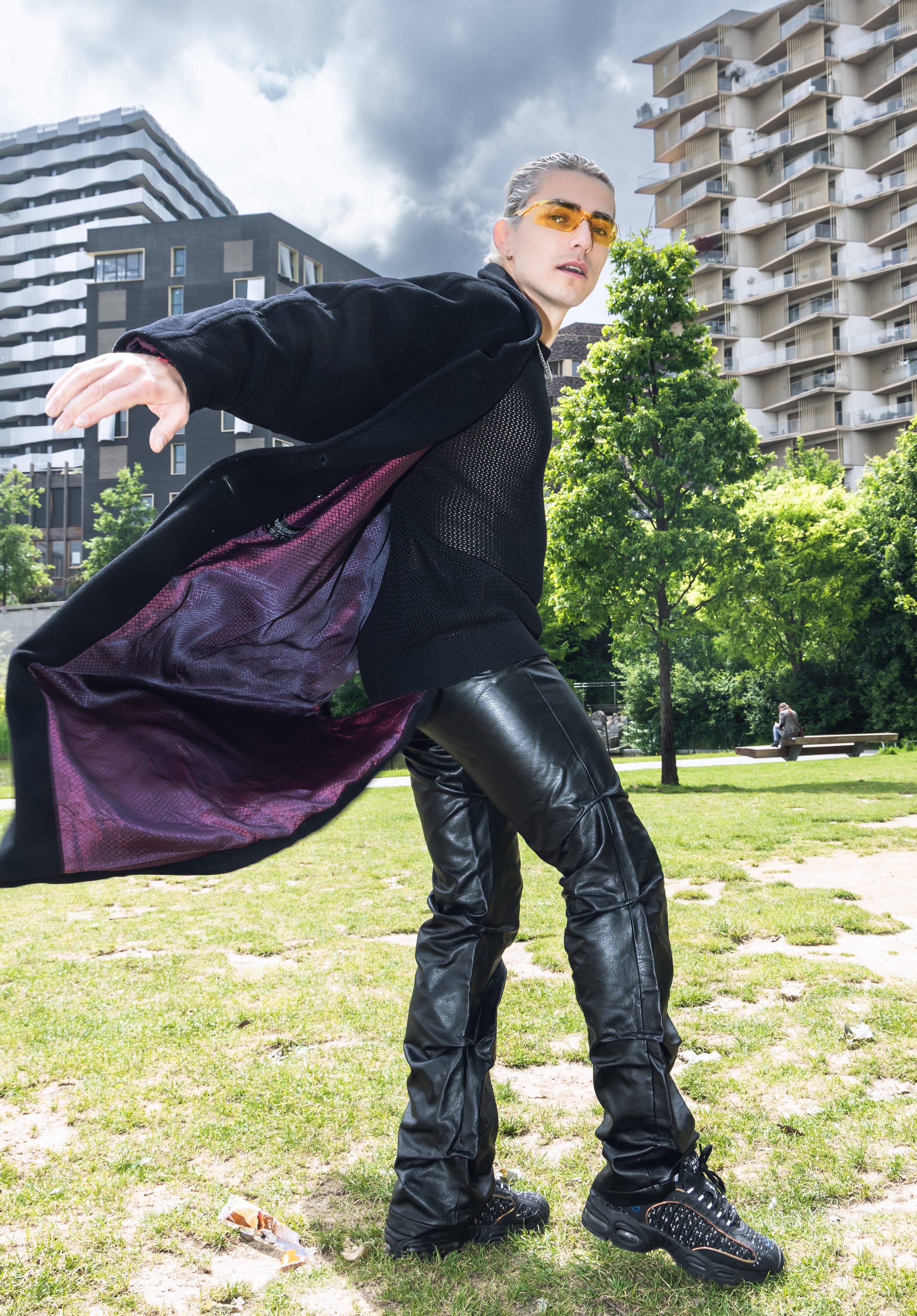 Fabio Di Domenico, manteau doublé de violet ouvert dans le vent, sur une pelouse.