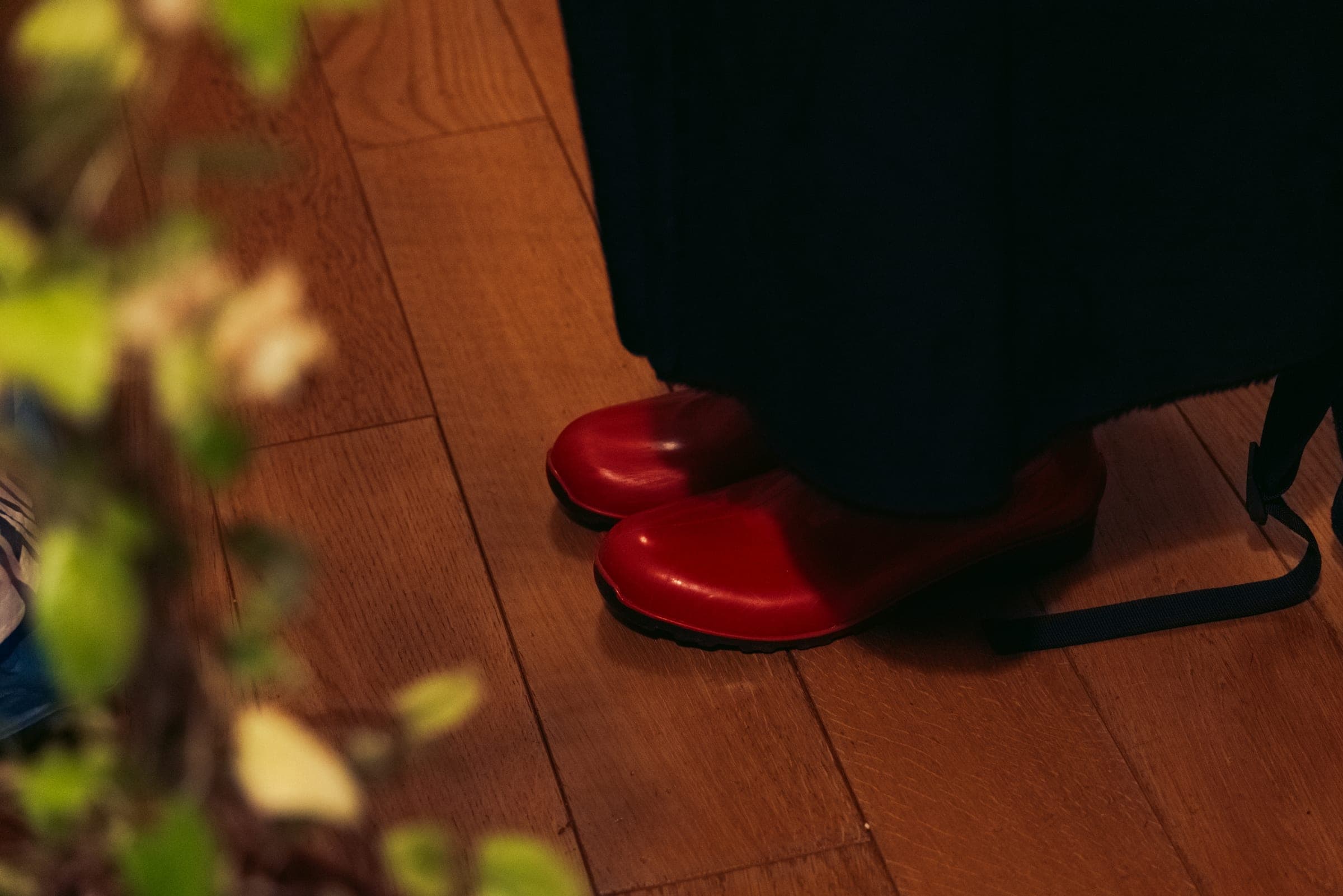 Une paire de chaussures rouges vernies sur un parquet, sous une jupe noire