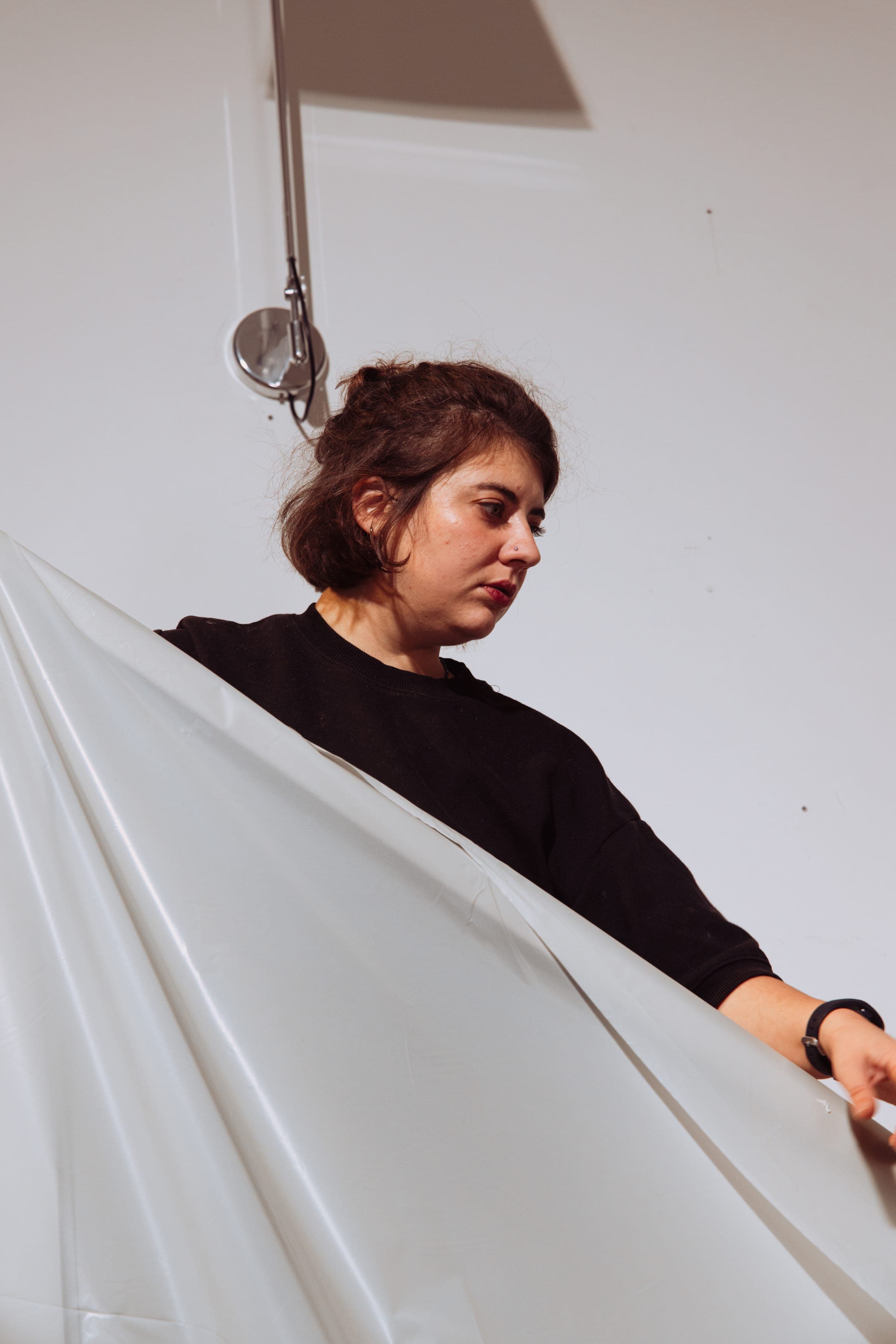 Une femme tend une grande feuille de papier blanc en guise de réflecteur