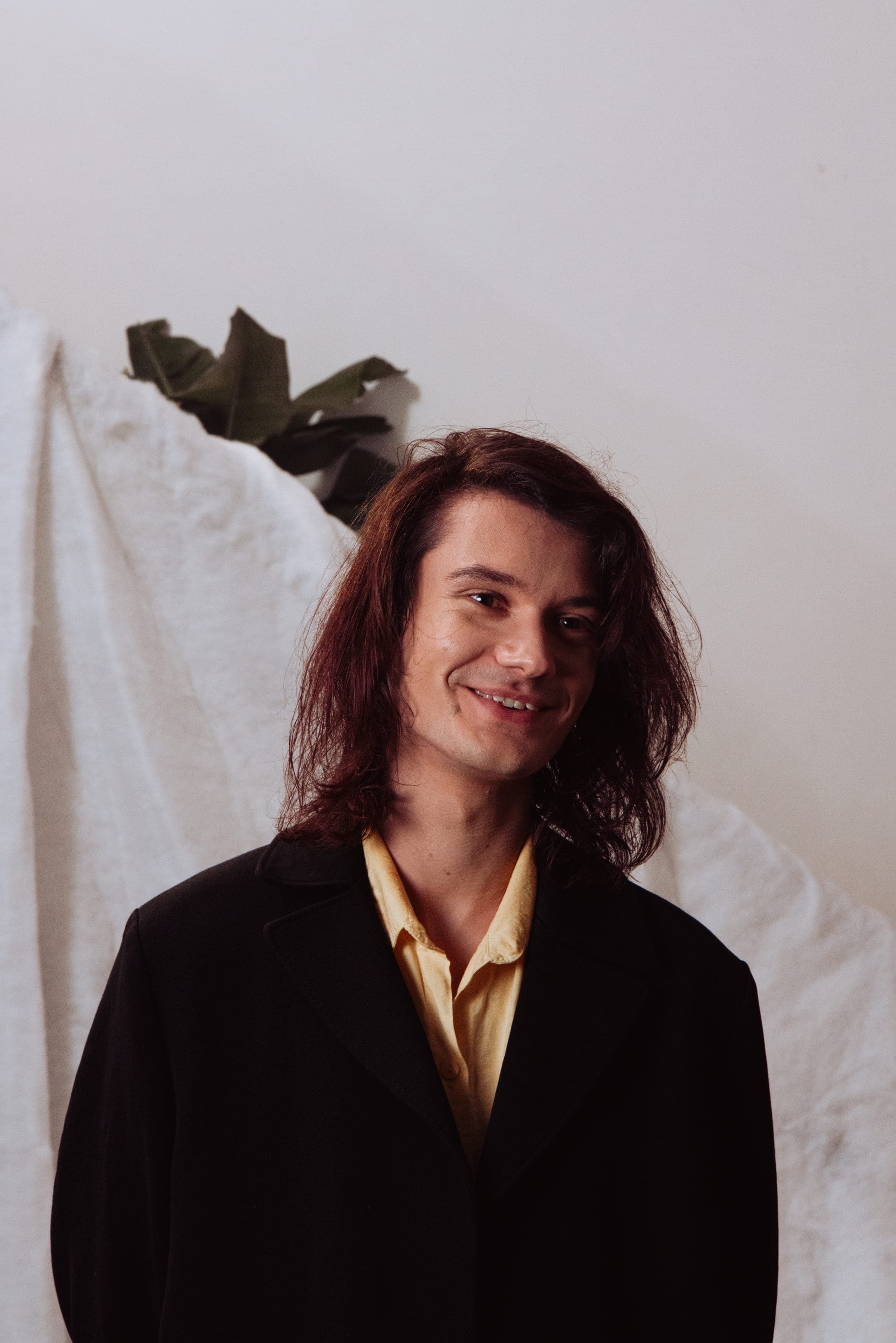 Le comédien en manteau noir et chemise jaune, souriant
