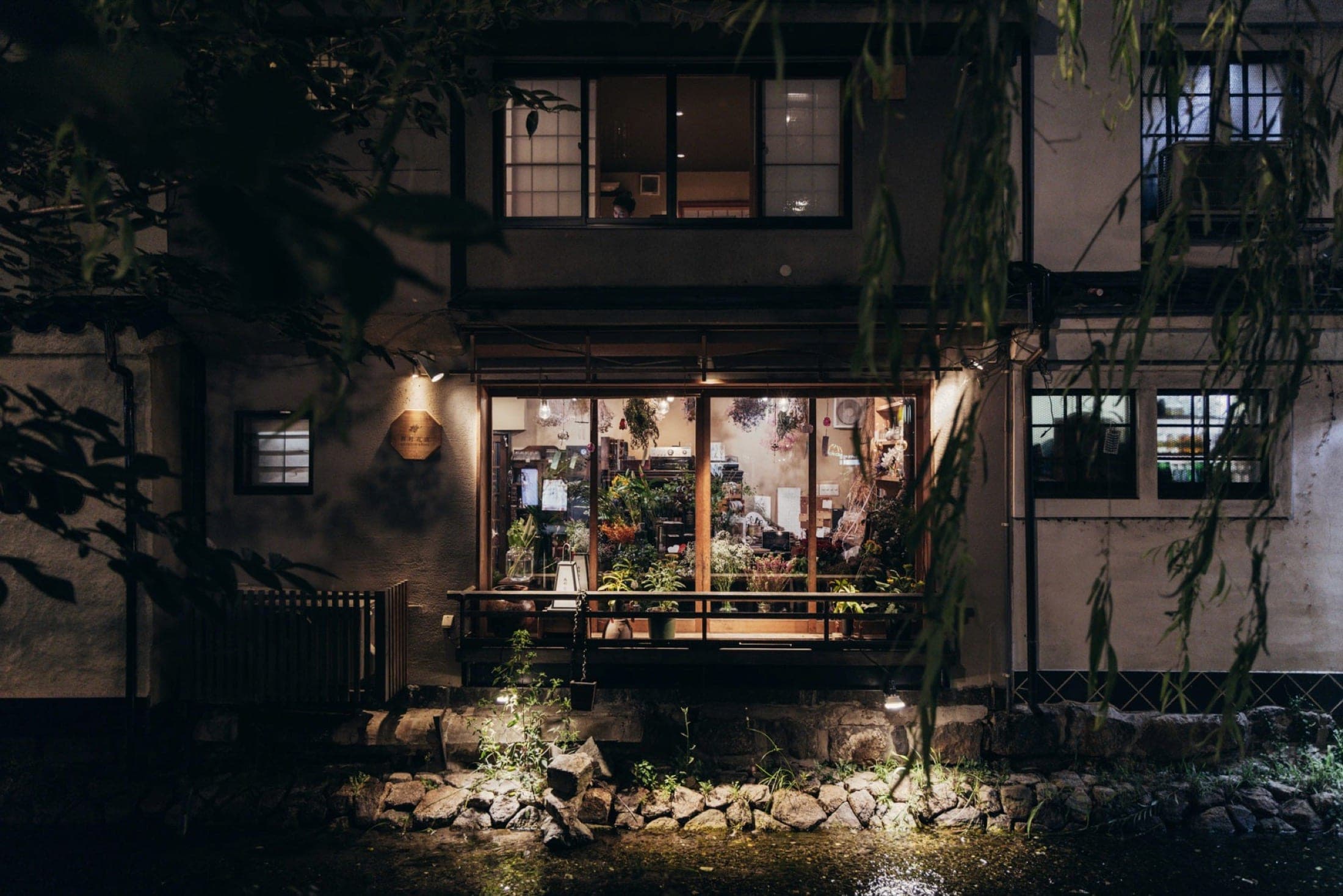 Maison traditionnelle japonaise éclairée au bord d'un canal, la nuit