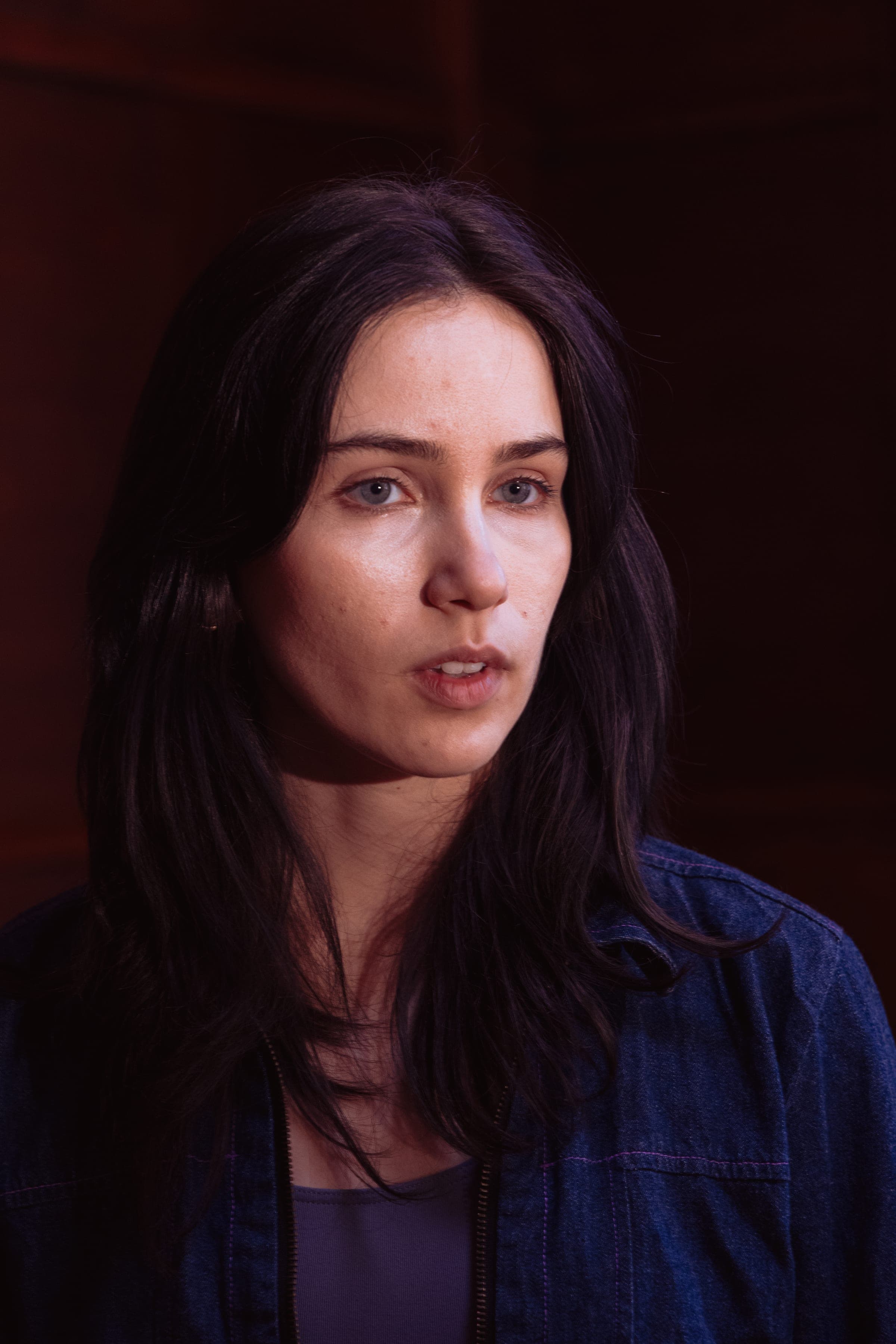 Portrait de la comédienne en veste en jean, elle parle face à l'objectif.