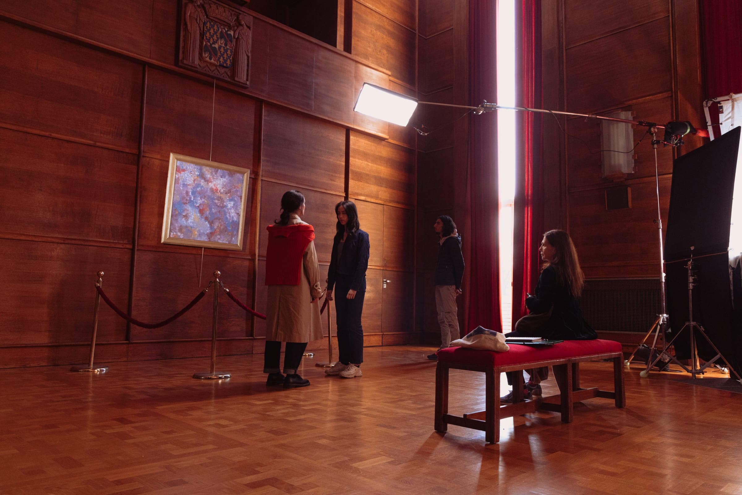 Plan large de la salle lambrissée : le tableau, le cordon, les projecteurs et l'équipe assise.