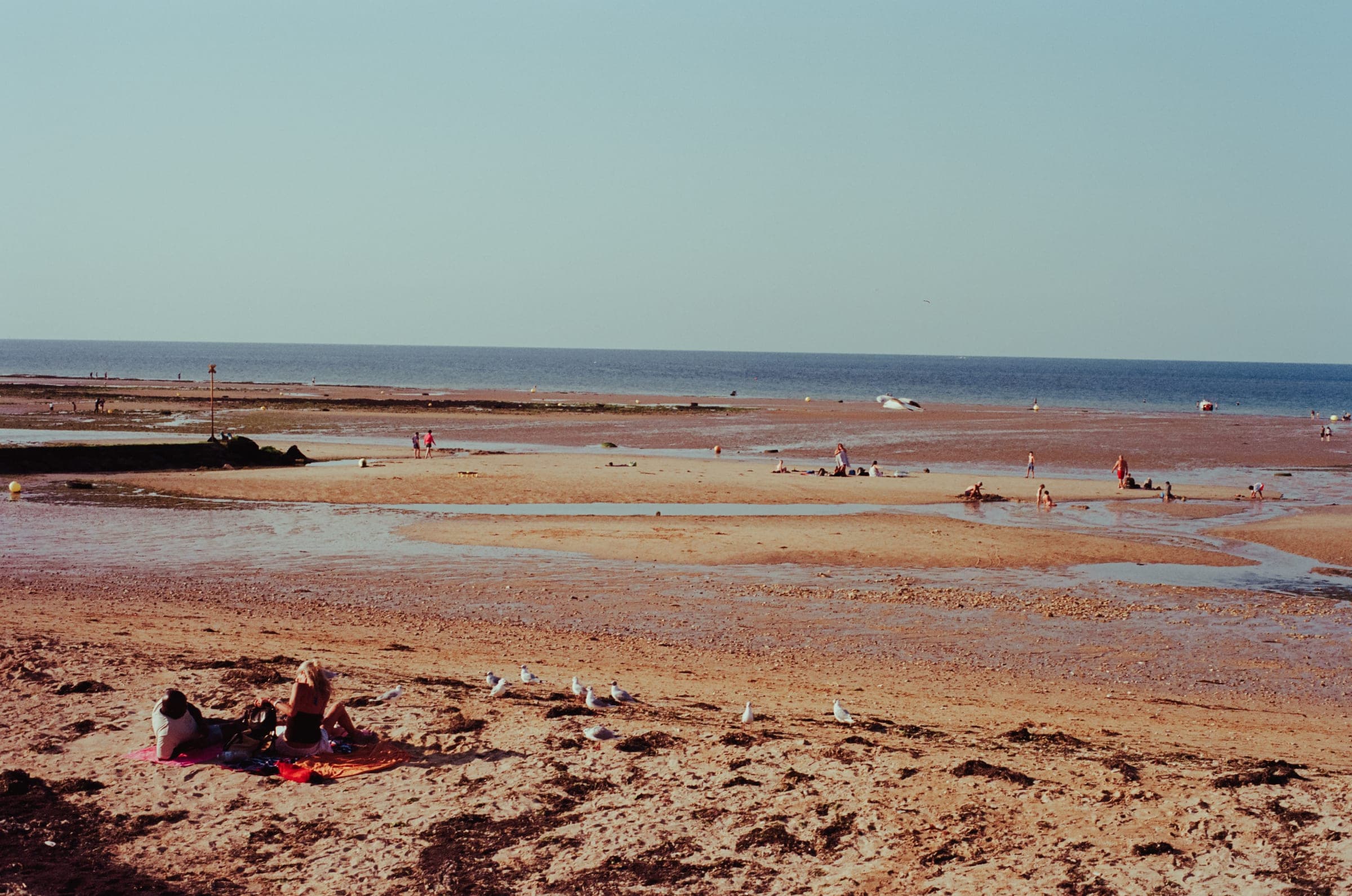 Marée basse à Langrune-sur-Mer, quelques baigneurs éparpillés sur l'estran.