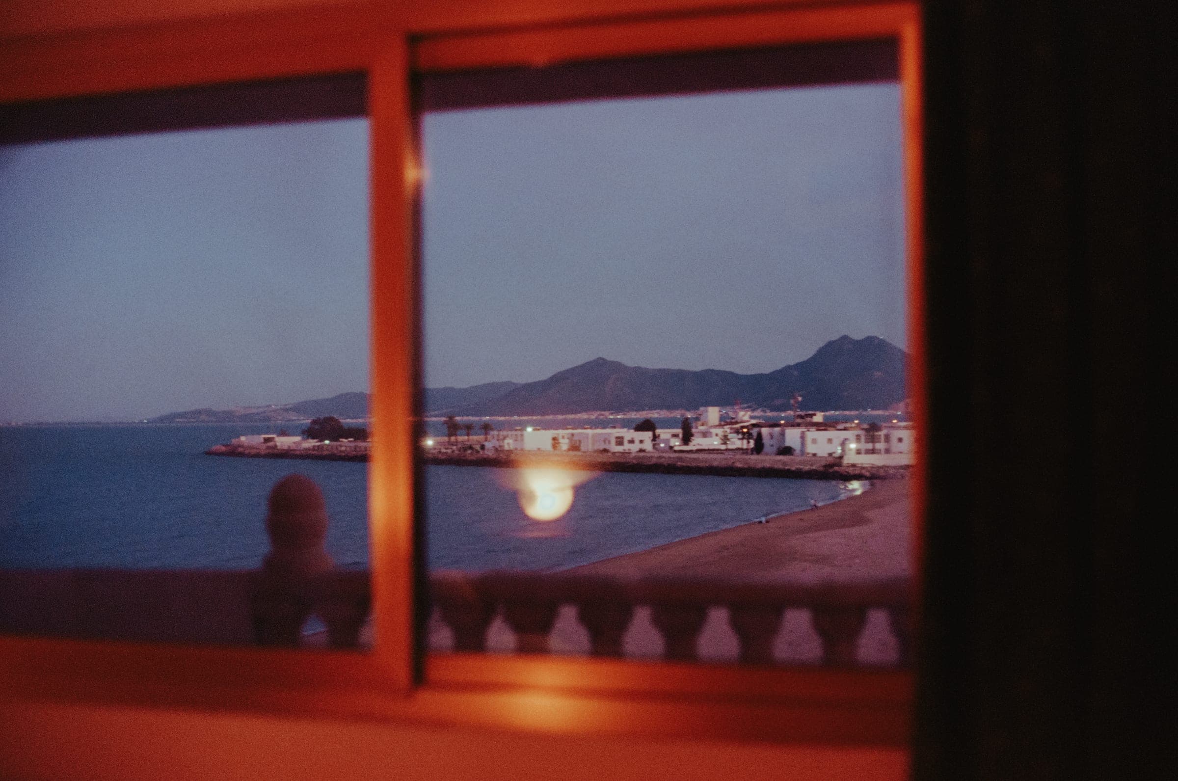 Le reflet de la baie de Tunis dans une fenêtre encadrée de bois.