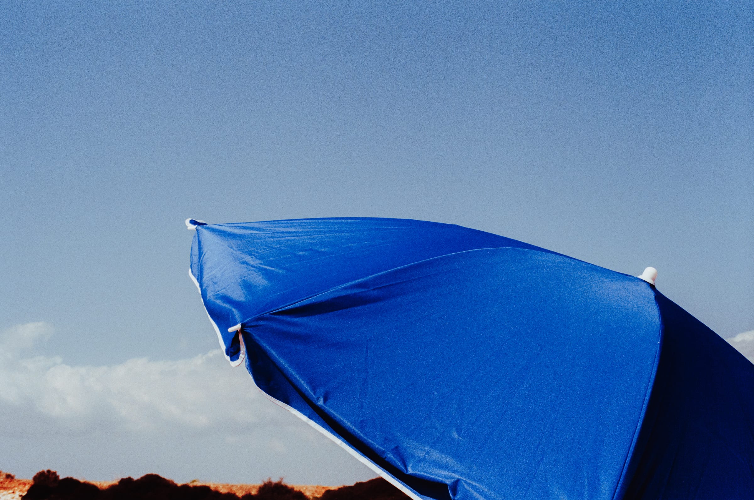Un parasol bleu vif contre le ciel.